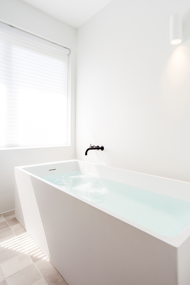 Maatwerk badkamer in Zwolle met Not Only White vrijstaand bad Axis en Modular verlichting. Kranen mat zwart van Vola, ontwerp Oliver Drent voor Studio Doccia.