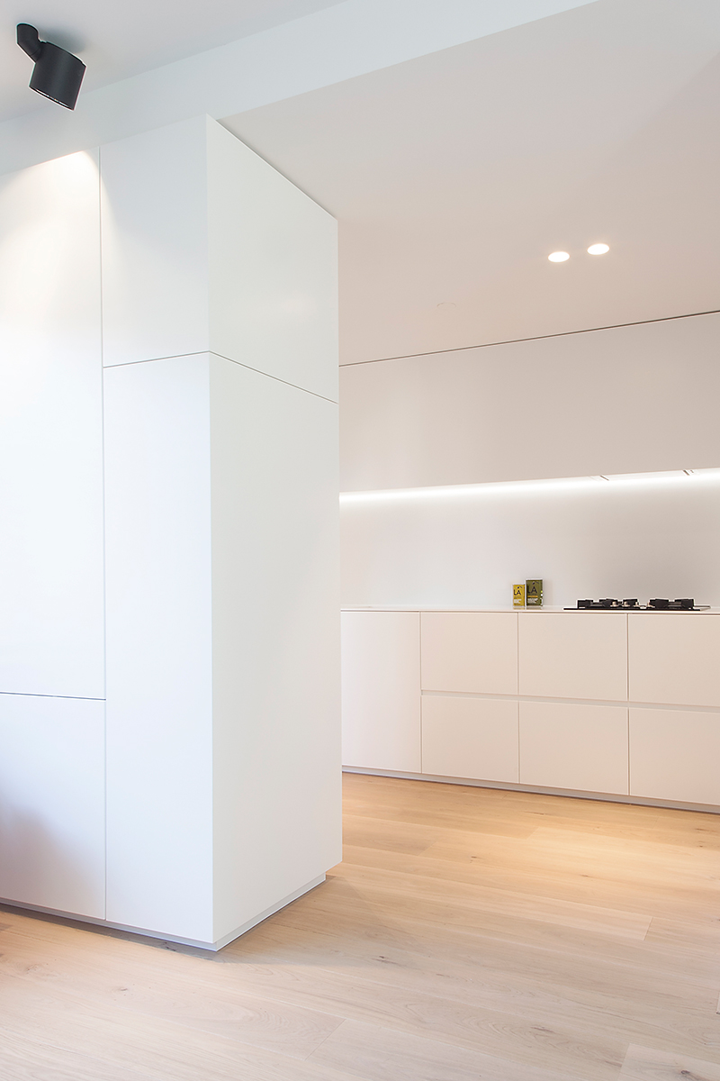 Maatwerk witte keuken in Corian door Studio Doccia, verlichting Modular. De eikenhouten vloer zorgt voor de warme toevoeging.